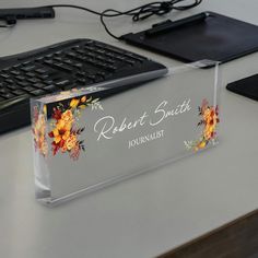 a clear acrylic business card holder sitting on top of a desk next to a keyboard