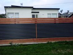 a house behind a wooden fence in the grass