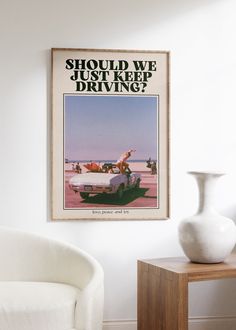 a white chair sitting next to a table with a vase on it and a poster above it