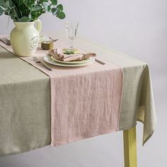 the table is set with a plate, fork and knife on it next to a potted plant