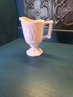 a white cup sitting on top of a green table