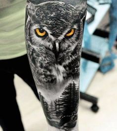 an owl with yellow eyes and trees on it's arm is shown in black and white