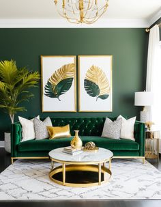 a living room with green velvet couches, gold accents and paintings on the wall