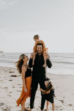 a family on the beach with their toddler son and mom holding him up in the air