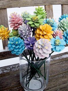 a vase filled with colorful flowers sitting on top of a wooden bench