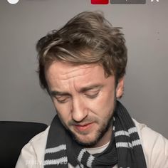 a man wearing a scarf looking down at his cell phone