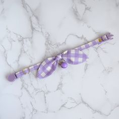 a purple and white checkered umbrella on a marble counter top with a ribbon tied around it