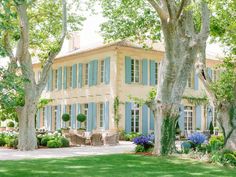 a large house with blue shutters and trees