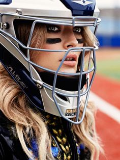 a woman wearing a football helmet with her face painted like an american flag on it