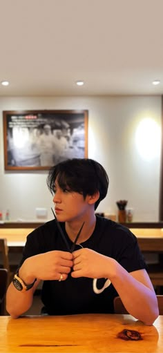 a young man sitting at a wooden table