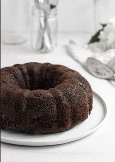 a bundt cake sitting on top of a white plate next to a glass vase