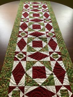 a quilted table runner with red and green designs