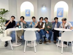 five people sitting on a blue couch with white chairs and tables in front of them