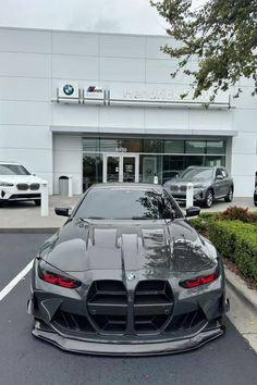 a black sports car parked in front of a bmw dealership