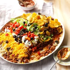 a white plate topped with mexican food next to a bowl of salsa and tortilla chips