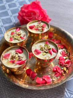 four small cups filled with food on top of a metal tray next to a red rose