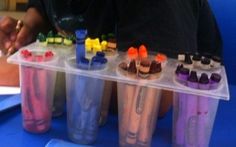 a person sitting on the ground with some cups in front of them and writing on paper