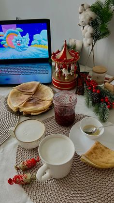 a laptop computer sitting on top of a table next to plates and bowls filled with food