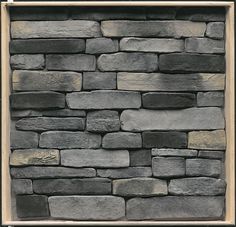 a stone wall with a wooden frame in the middle and some black rocks on it