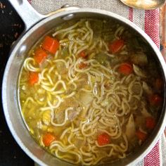 a pot full of soup with noodles and carrots