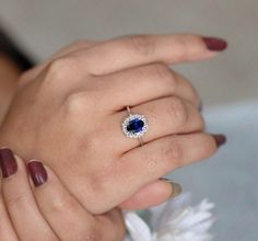 a close up of a person wearing a ring with a blue stone in the middle