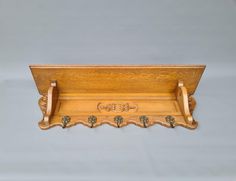 a wooden shelf with three coat hooks on the top and two leaves on the bottom