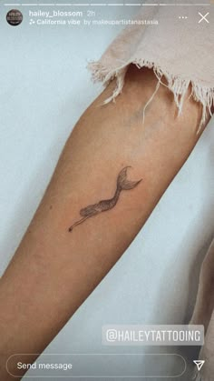 a woman's arm with a small bird tattoo on the left side of her arm