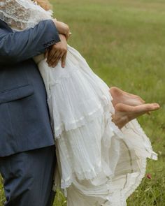 a man in a suit and tie holding a woman's dress while standing in a field