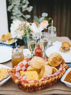 a basket full of food sitting on top of a table next to plates and glasses