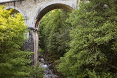 an old stone bridge over a river surrounded by trees