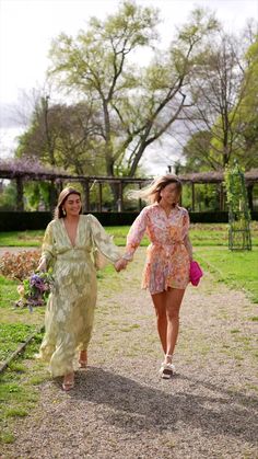 two women walking down a path holding hands