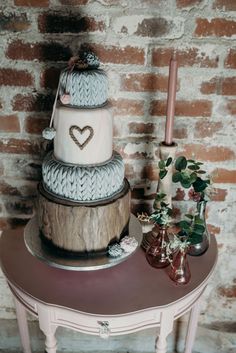 a three tiered cake sitting on top of a wooden table next to a brick wall