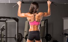 a woman standing in the middle of a gym with her back turned to the camera