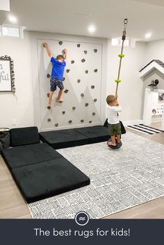 two children climbing on the wall in a playroom with black and white rugs