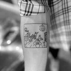 a black and white photo of a person with a cartoon tattoo on his arm