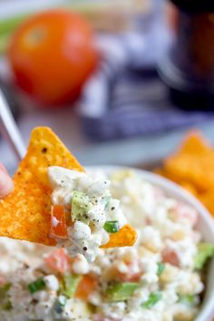 a person holding up a tortilla chip with guacamole and salsa