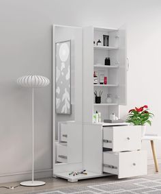 a white cabinet with two drawers and a mirror on the wall next to a plant