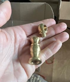 a person is holding two small brass fittings in their hand, one has a screw and the other has a nut