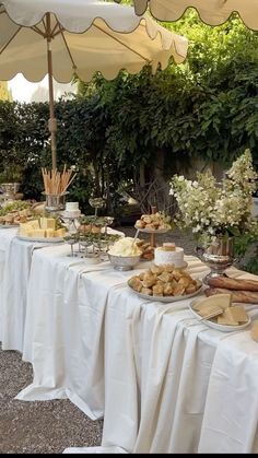 a table covered in lots of food under an umbrella