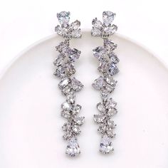 two pairs of diamond earrings sitting on top of a white plate