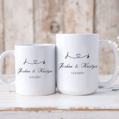 two white coffee mugs sitting on top of a table