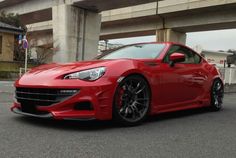 a red sports car parked in front of an overpass