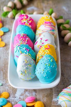 colorfully decorated donuts in a white tray with sprinkles on them