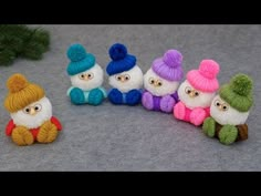 small knitted gnomes sitting next to a pine tree on a gray surface,