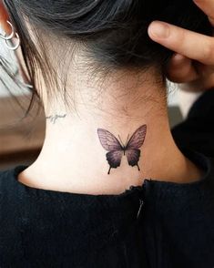 a woman's neck with a small butterfly tattoo on the back of her neck