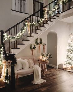 a living room filled with furniture and christmas lights on the staircases, along with garlanded trees