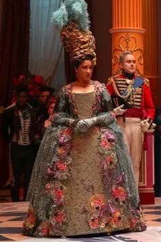 a woman in a dress with flowers on it and a man in uniform standing next to her