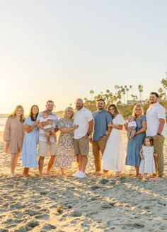 a group of people standing on top of a sandy beach next to the ocean with palm trees