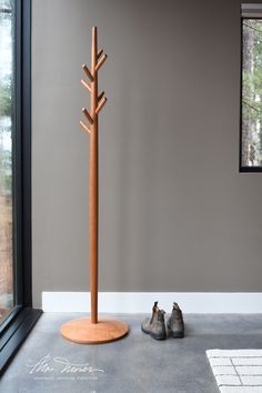 A cherry coat tree by Thos Moser is in a cement-floored room with putty-colored walls. It has a domed base and seven turned coat hooks. Beside the coat tree is a pair of boots. Coat Tree Diy, Spindle Chairs, Clothes Tree, Spindle Chair, Coat Tree, Nitty Gritty, Hanging Clothes, Functional Storage, Tree Designs