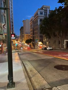 an empty city street at night with cars driving on it and buildings in the background